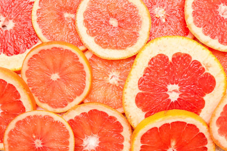 Slices of juicy ripe grapefruit as background, closeupの写真素材