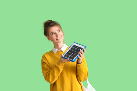 Pretty young woman with portable solar panel on green backgroundの写真素材
