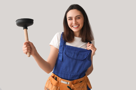 Female plumber with plunger on gray backgroundの写真素材