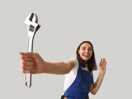Female plumber with wrench on gray background, closeupの写真素材