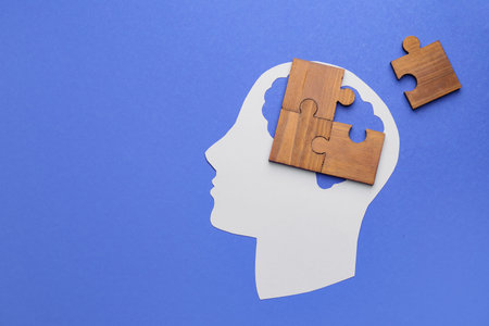 Paper human head and pieces of jigsaw puzzle on color background. concept of dementia