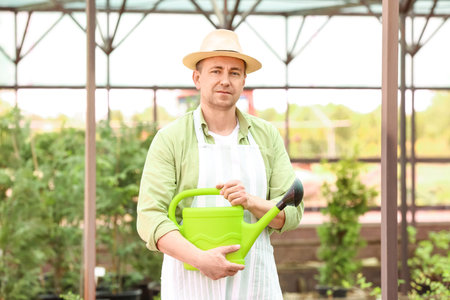 Male gardener with watering can in greenhouseの写真素材