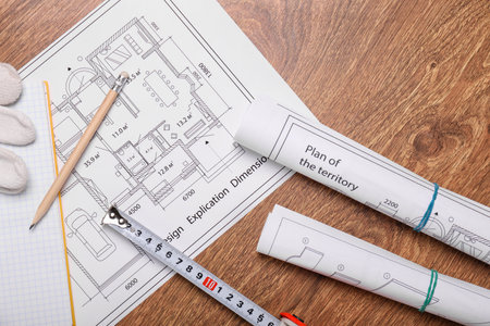 Measuring tape with blueprints on wooden backgroundの写真素材