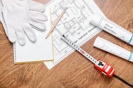Measuring tape with blueprints on wooden backgroundの写真素材