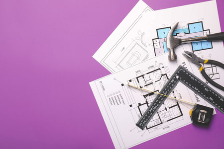 Measuring tape with builder's supplies and blueprints on color backgroundの写真素材