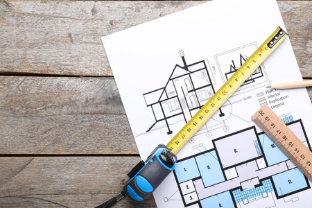 Measuring tape with blueprint on wooden backgroundの写真素材