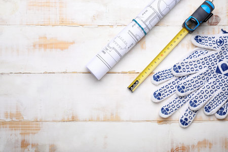 Measuring tape with gloves and blueprint on wooden backgroundの写真素材