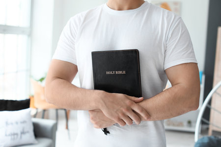 Young man with Bible at home, closeupの写真素材