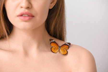 Beautiful young woman with butterfly on light background, closeupの写真素材