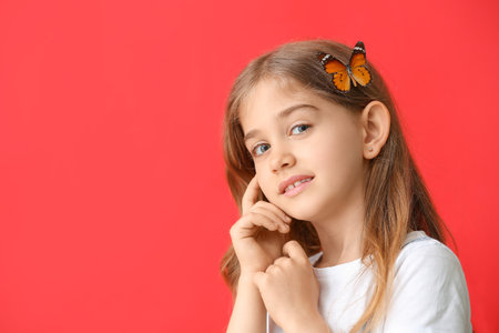 Cute little girl with butterfly on color backgroundの写真素材