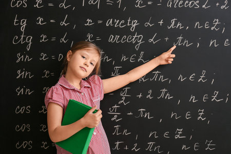 Cute little schoolgirl near blackboard in classroomの写真素材