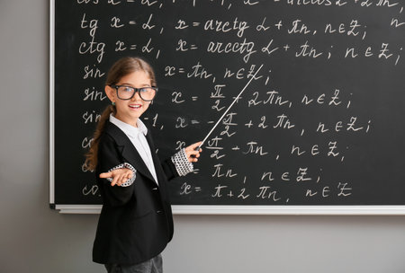 Cute little schoolgirl near blackboard in classroomの写真素材