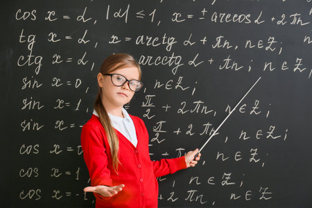 Cute little schoolgirl near blackboard in classroomの写真素材
