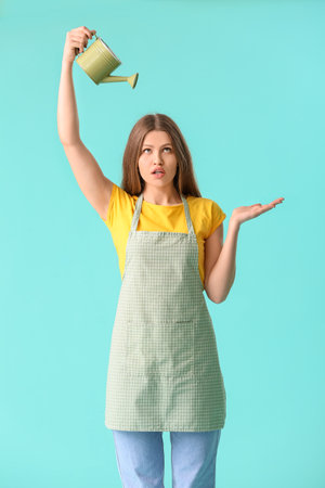 Young woman with watering can on color backgroundの写真素材