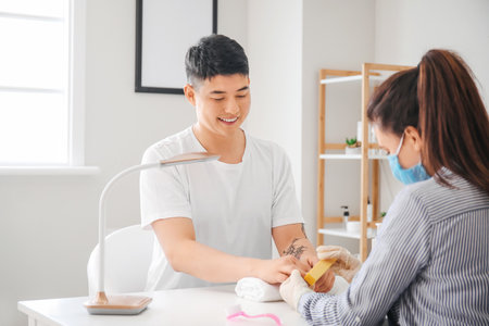 Manicure master working with male client in beauty salonの写真素材