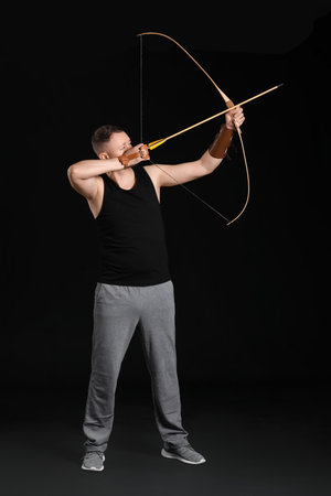Handsome male archer with bow on dark backgroundの写真素材