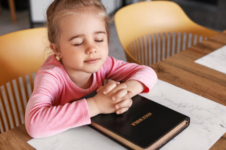 Little girl with Bible praying at homeの写真素材
