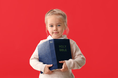 Little girl with Bible on color backgroundの写真素材