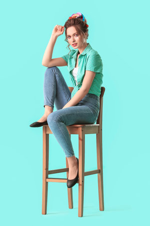 Beautiful young woman with unusual hair sitting on chair against color backgroundの写真素材
