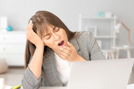 Young woman suffering from sleep deprivation in officeの写真素材