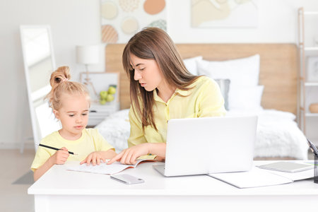 Working mother with her little daughter at homeの写真素材