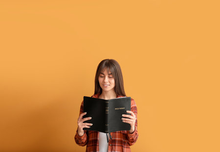 Young woman with Bible on color backgroundの写真素材