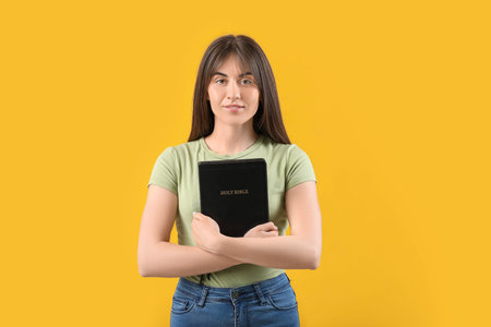 Young woman with Bible on color background