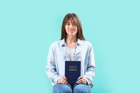 Young woman with Bible on color backgroundの写真素材