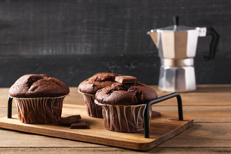 Board with tasty chocolate cupcakes on wooden tableの写真素材