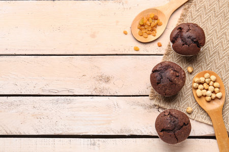Tasty chocolate cupcakes with raisins and hazelnuts on light wooden backgroundの写真素材