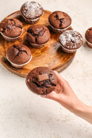 Woman holding tasty chocolate cupcake on light backgroundの写真素材