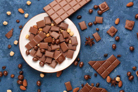 Composition with pieces of tasty chocolate, candies and nuts on color background