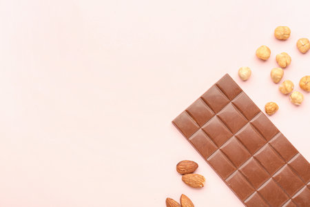 Tasty chocolate bar and nuts on color backgroundの写真素材
