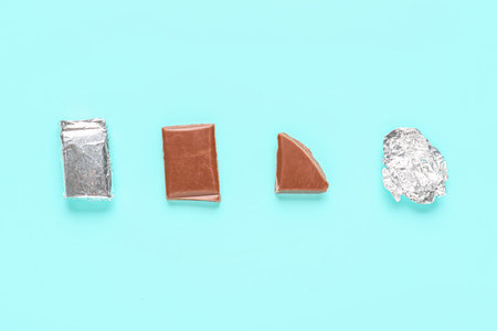 Composition with pieces of tasty chocolate and foil ball on color backgroundの写真素材