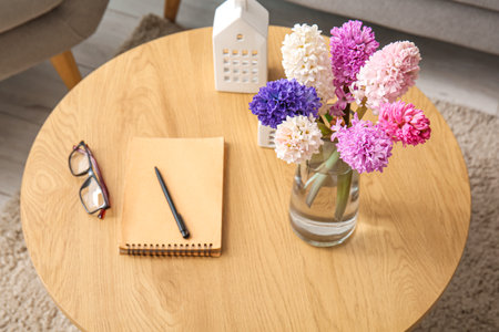 Vase with beautiful hyacinth flowers, glasses and notebook on coffee table, closeupの写真素材