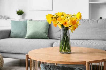 Vase with beautiful narcissus flowers on coffee table in living roomの写真素材
