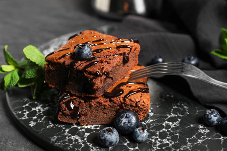Board with pieces of tasty chocolate brownie on black backgroundの写真素材