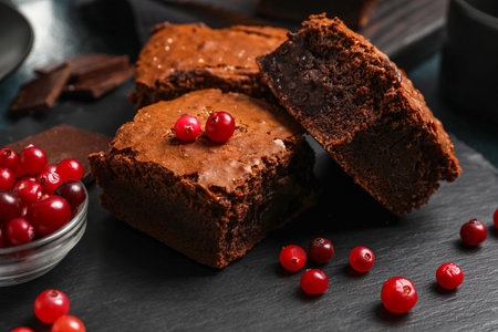 Board with pieces of tasty chocolate brownie on black backgroundの写真素材