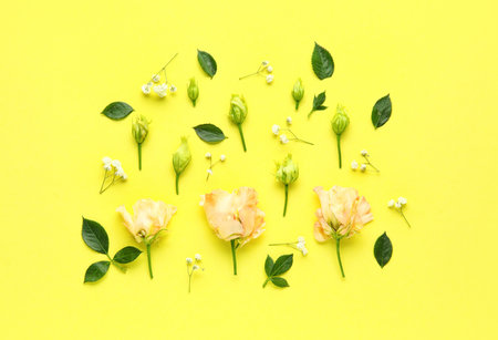 Composition with beautiful eustoma, gypsophila flowers and plant leaves on yellow backgroundの写真素材