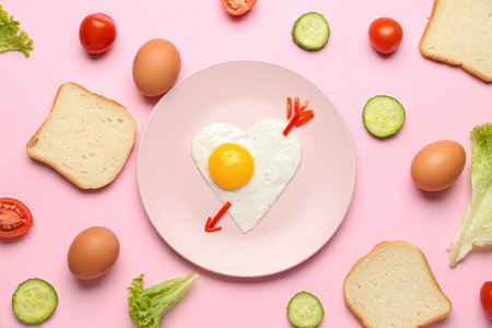 Plate with cute children's breakfast, eggs, vegetables and bread on pink backgroundの写真素材