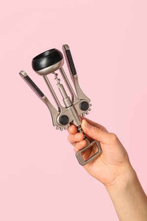 Female hand holding wine opener on pink backgroundの写真素材