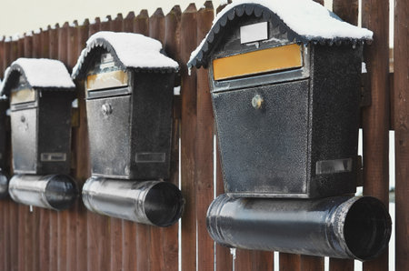 View of metal mailboxes with snow on wooden fence, closeupの写真素材