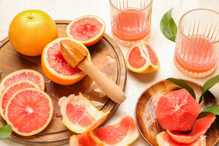 Cut ripe grapefruits, peel and glasses of juice on light background, closeupの写真素材