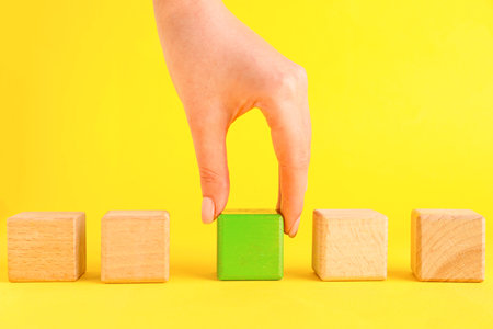 Woman with wooden cubes on yellow backgroundの写真素材