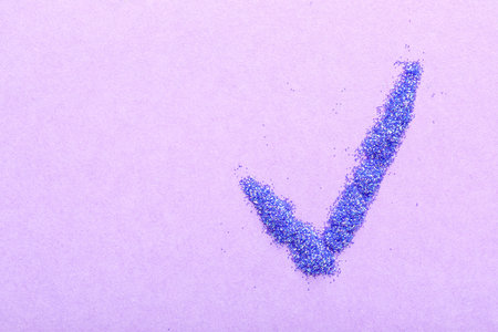 Check mark made of glitter on lilac backgroundの写真素材