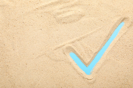 Check mark made of sand on blue backgroundの写真素材