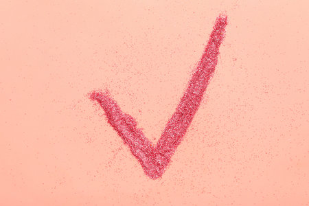 Check mark made of glitter on pink backgroundの写真素材