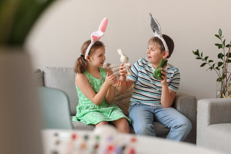 Little children playing with Easter rabbits on sofa at homeの写真素材