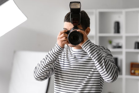Young male photographer with professional camera in studioの写真素材