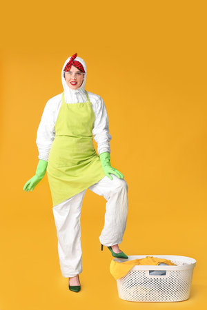 Housewife in protective suit and with laundry on color backgroundの写真素材